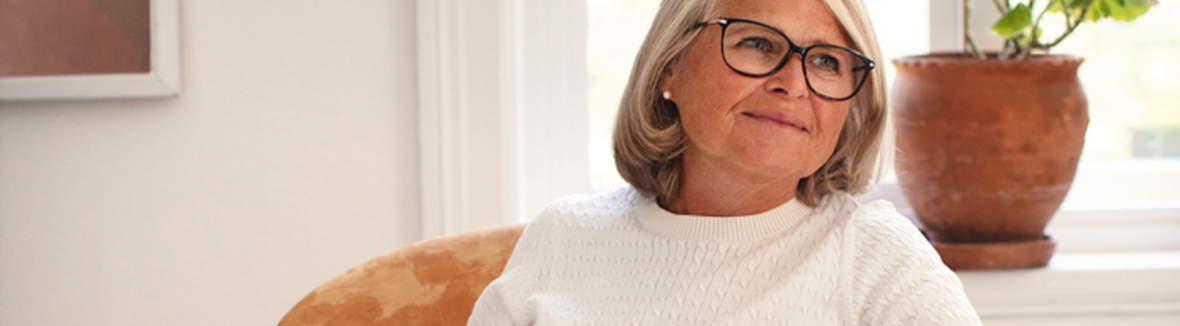 Eldre kvinne i stol som leser