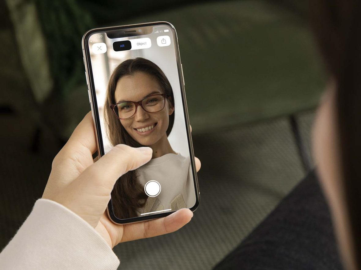 Kvinde med telefon i hånden prøver briller online
